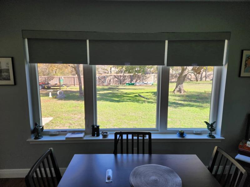 Three manual roller shades partially lowered over large triple window in dining room