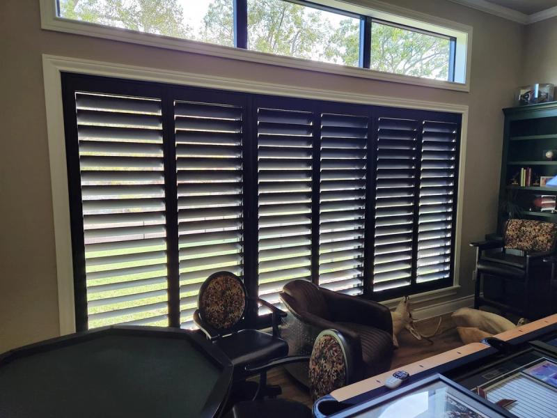 Dark shutters covering large interior window wall in home office