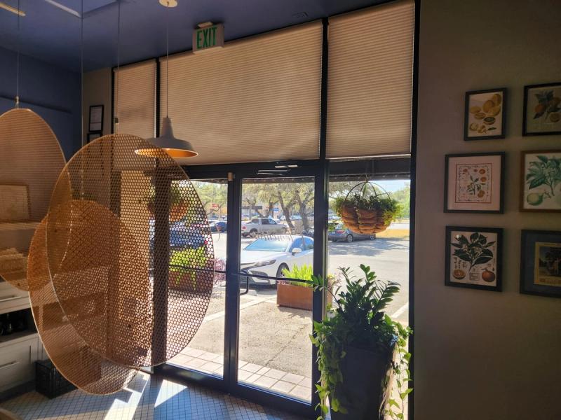Cellular honeycomb shades partially lowered on large storefront windows in retail interior