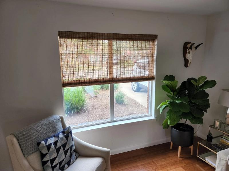 Woven wood bamboo roller shade partially lowered on wide living room window
