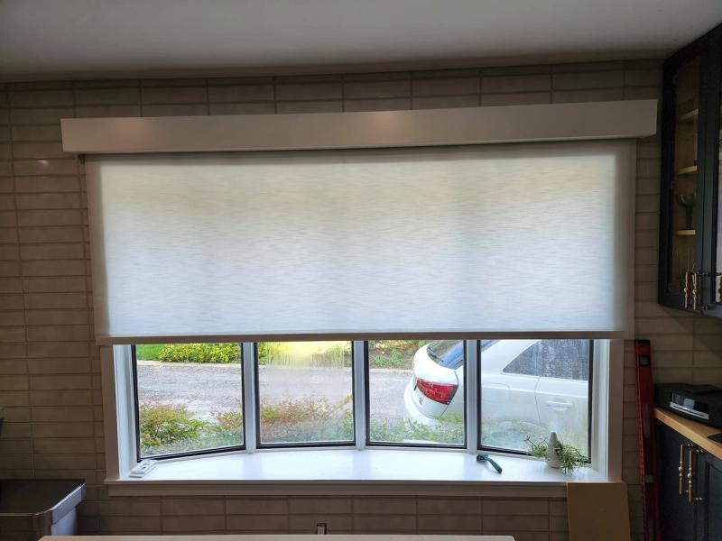 White roller shade partially lowered on wide kitchen window with tile backsplash