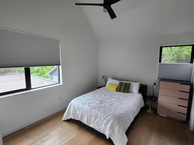 Cellular honeycomb shades on two windows in a modern bedroom with vaulted ceiling