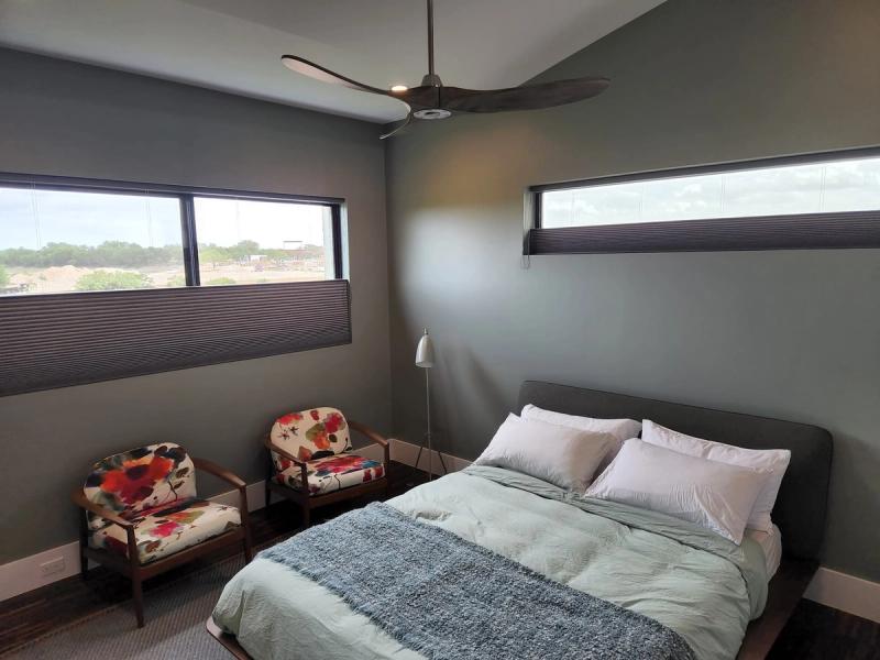 Cellular honeycomb shades on two horizontal clerestory windows in a modern gray bedroom