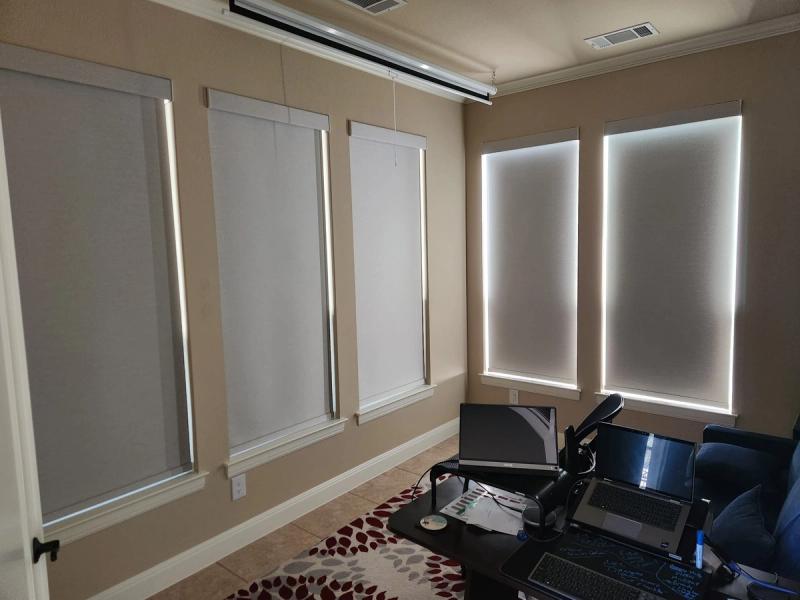 Roller shades on five windows in a home office with bright light edges