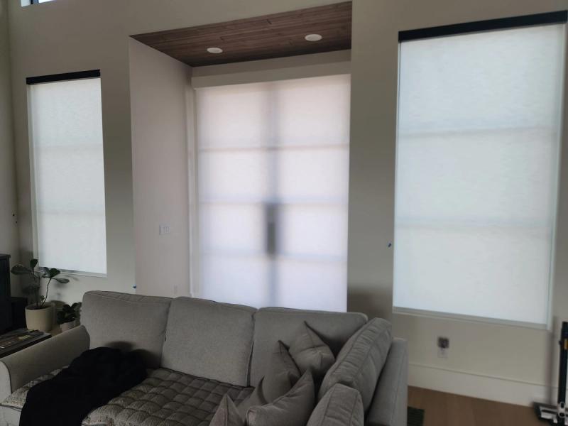 Solar roller shades on three windows in modern living room with gray sectional sofa