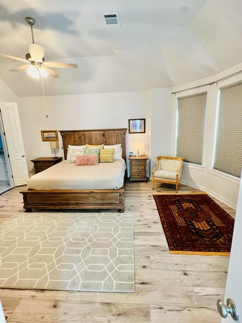 Bedroom with cordless cellular shades on two windows, vaulted ceiling, wooden bed