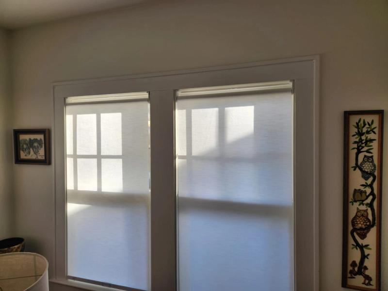 Two white solar roller shades on sliding glass patio doors, diffusing bright sunlight