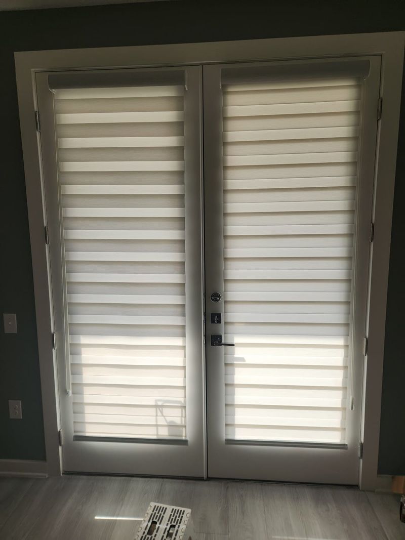 White cellular shades installed on double French doors in a modern interior room