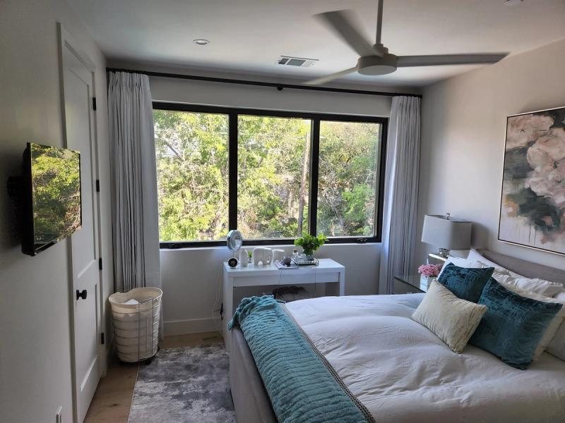 Sheer white drapery panels flanking large black-framed windows in a modern bedroom