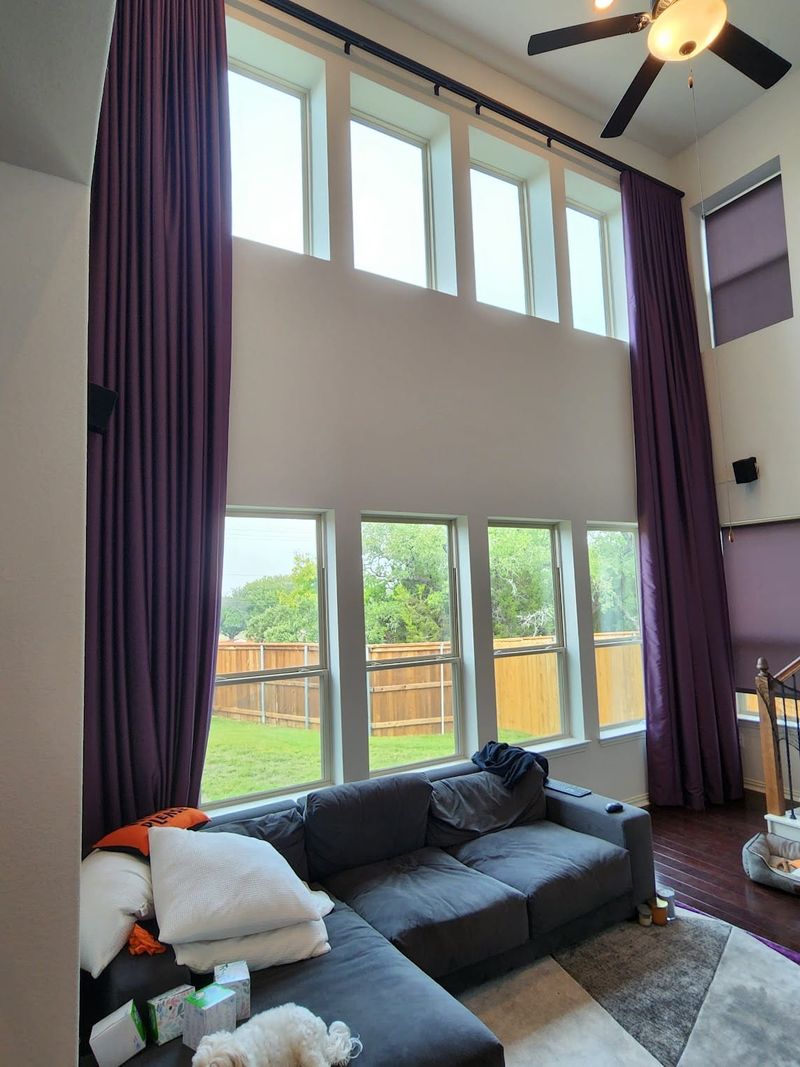 Floor-to-ceiling purple drapery panels in a two-story living room with large windows