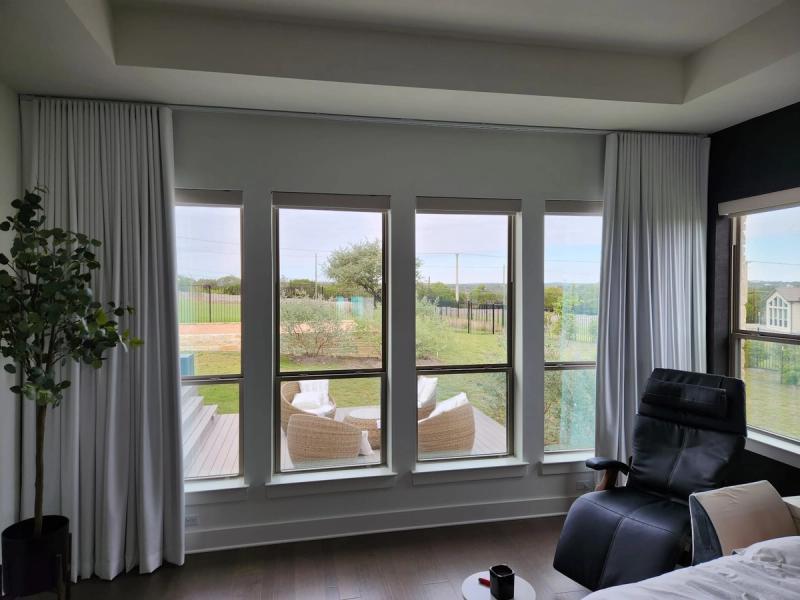 White ripple-fold drapery panels on ceiling track framing four tall windows in modern bedroom