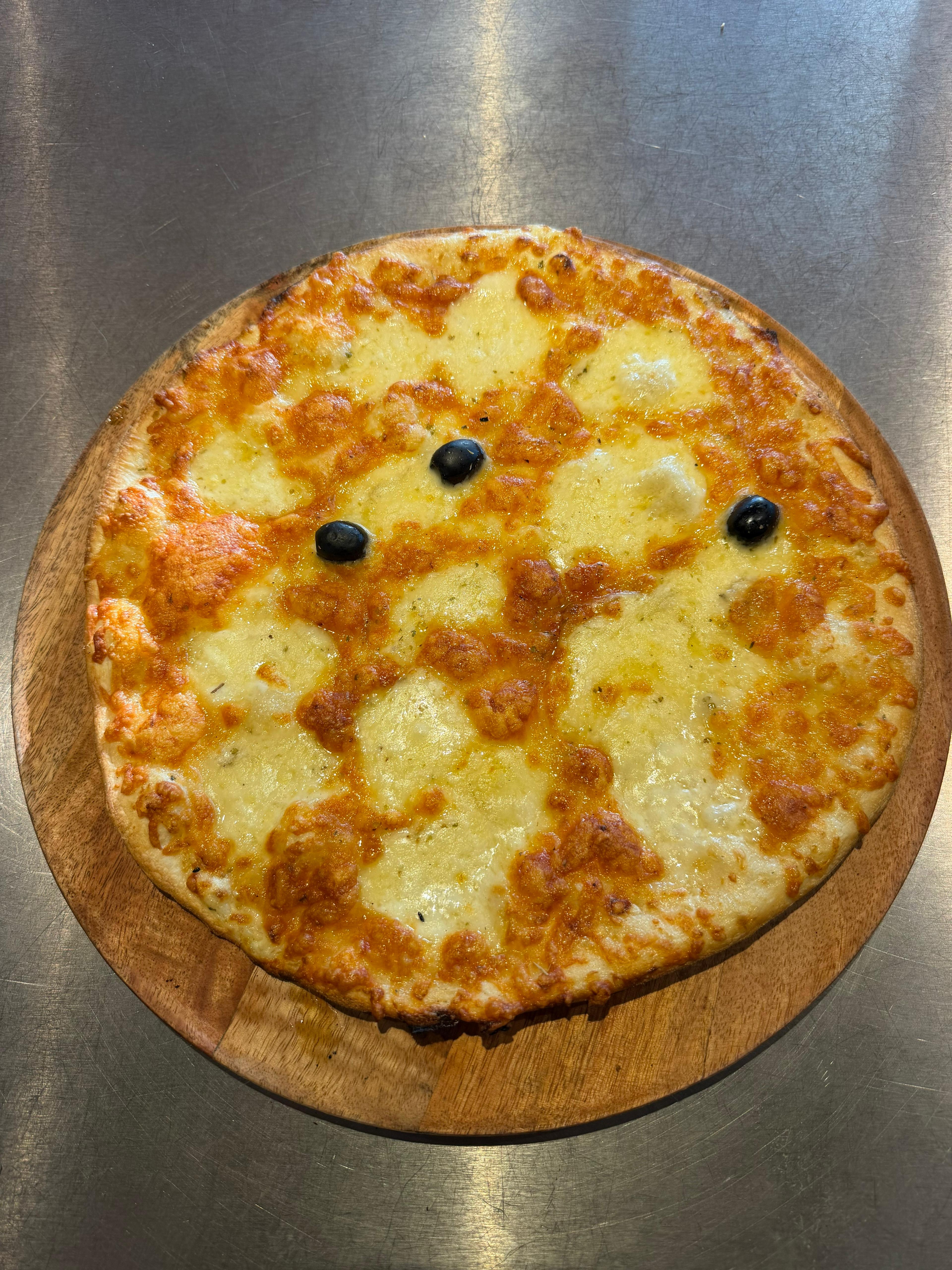 Pizza Margherita généreuse avec sa pâte dorée, garnie de mozzarella fraîche, d'un mélange d'emmental fondu et de quelques olives noires.