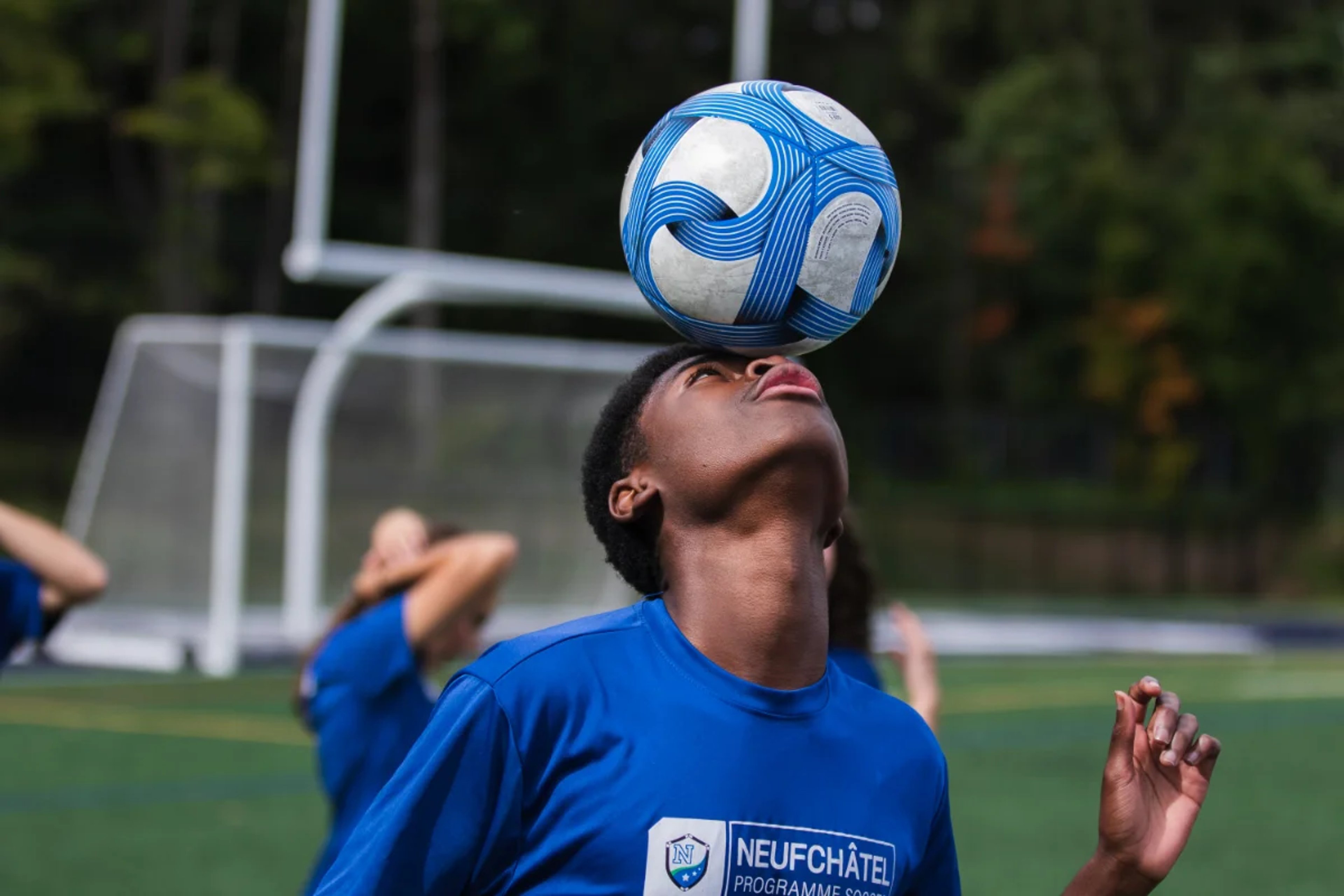 Un jeune joueur garde le ballon en équilibre sur son front pendant un entraînement de soccer