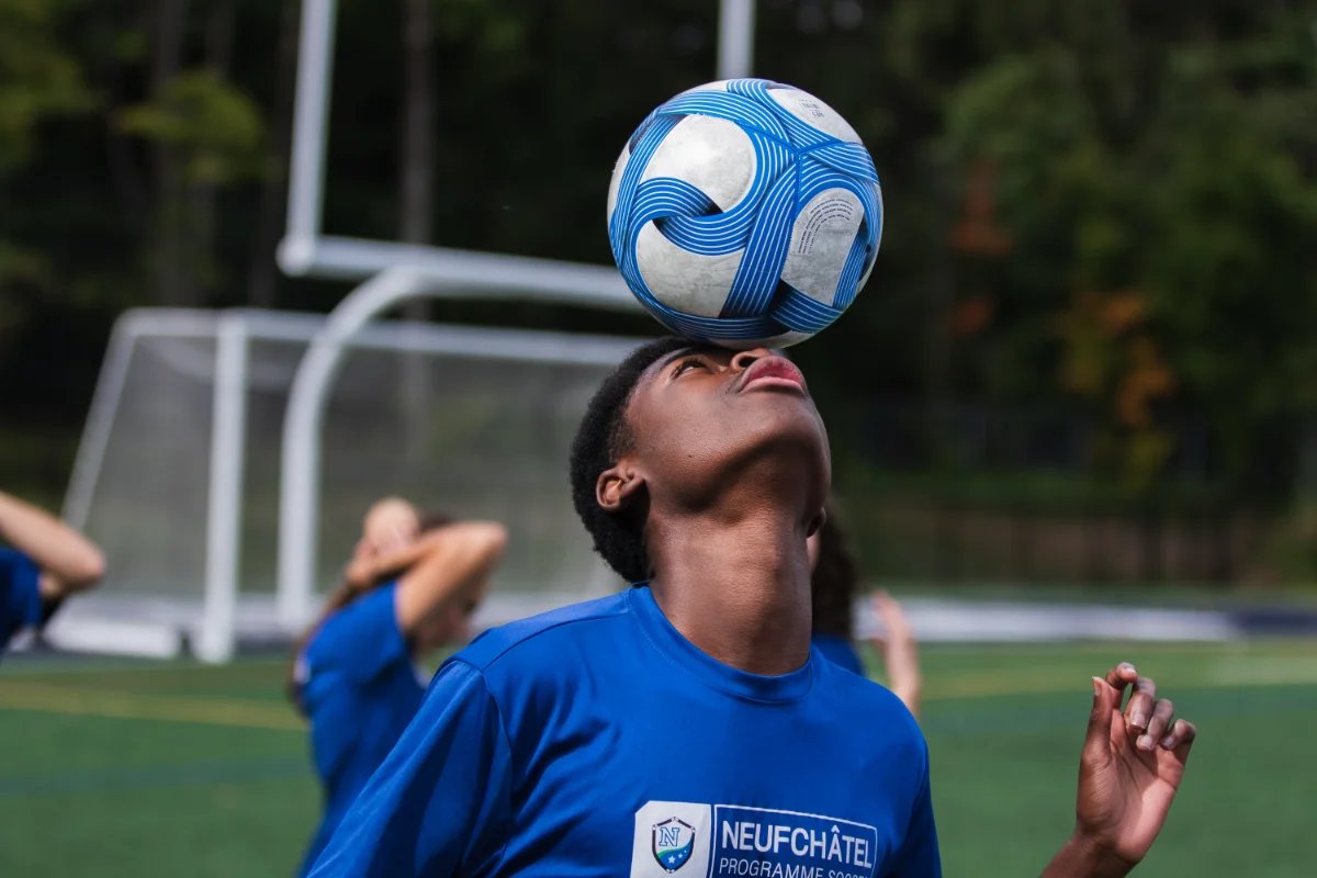 Un jeune joueur garde le ballon en équilibre sur son front pendant un entraînement de soccer