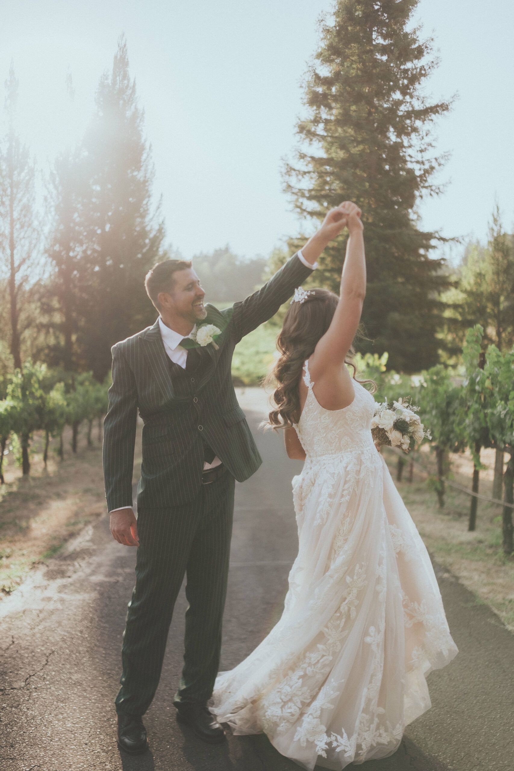 A couple dancing on a vineyard lane in warm evening light.