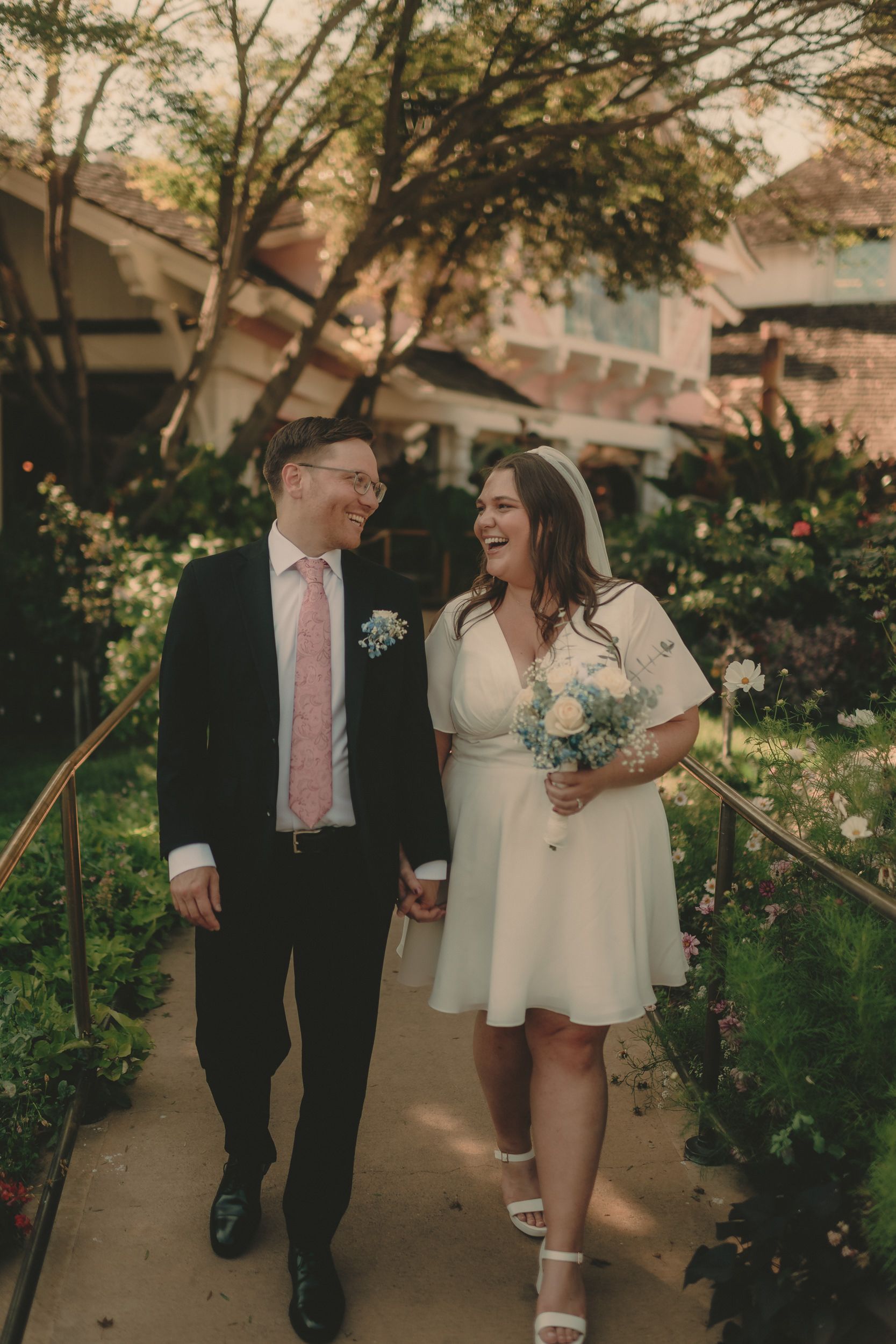 Tiffani and Braden laugh together on a flower-lined garden path.