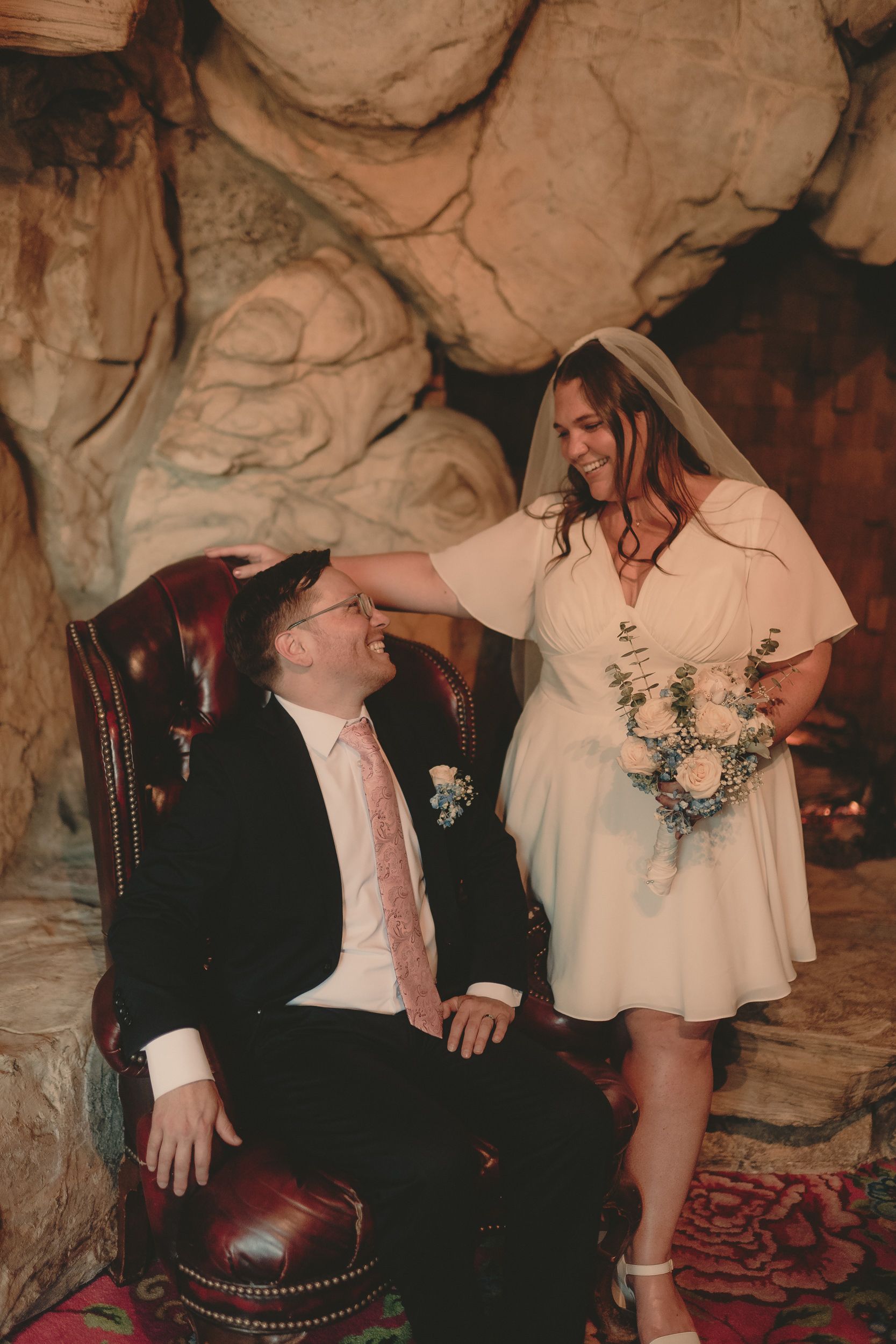 Tiffani and Braden embrace in a rock-lined Madonna Inn interior.