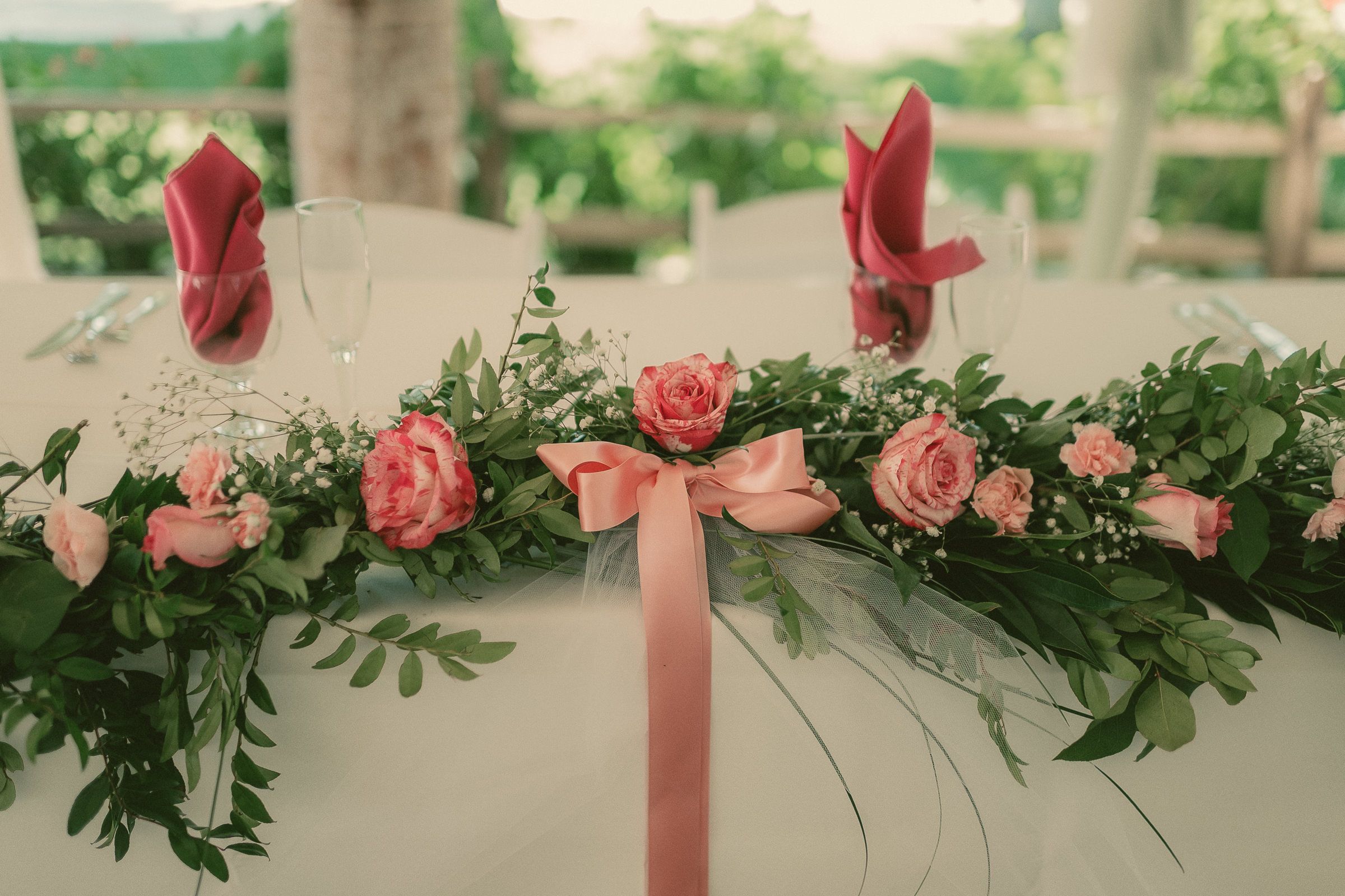 Peach and pink roses, trailing greenery, and ribbons on Caroline and Michele’s wedding table.