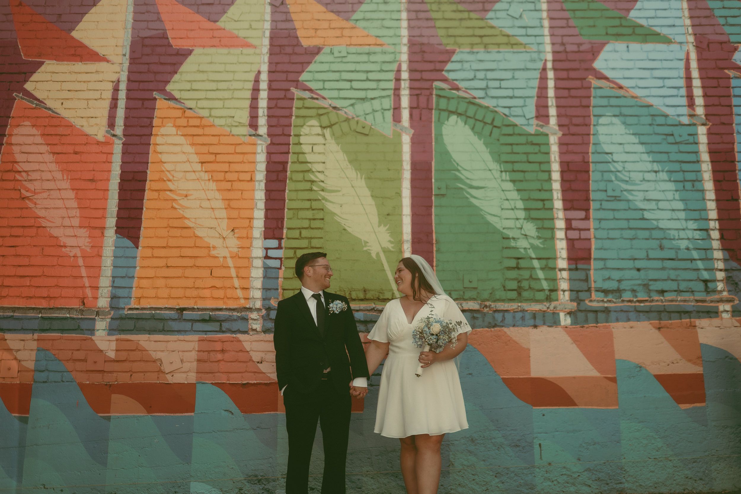 Tiffani and Braden stand beneath a colorful downtown San Luis Obispo mural before their courthouse elopement.