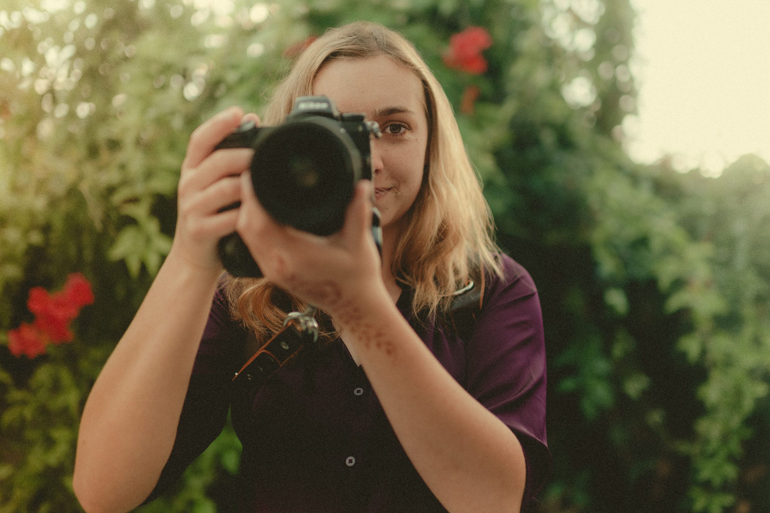 Makayla Grogan raising her camera to photograph a moment.