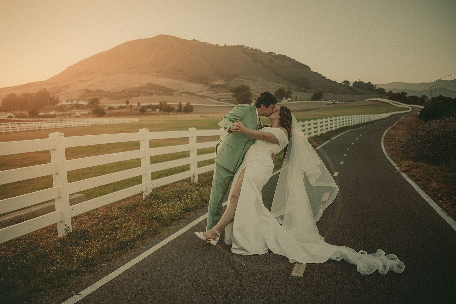 Newlyweds standing on a country road at sunset near the Madonna Inn
