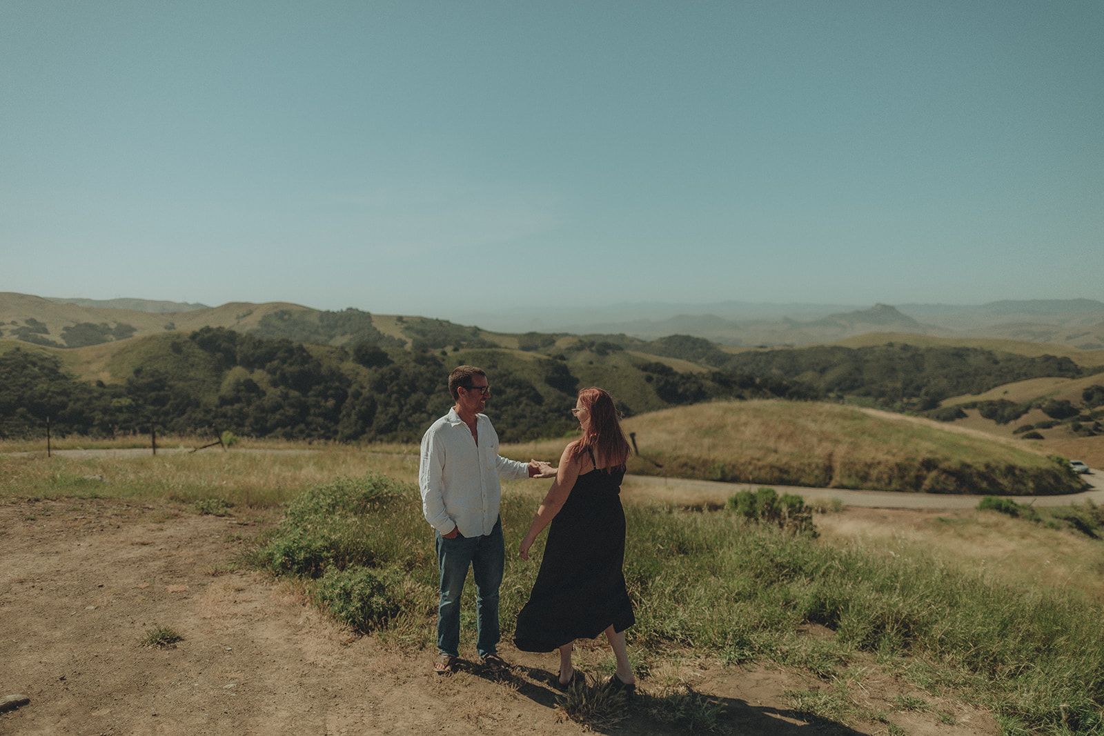Couple standing small against rolling Central Coast hills
