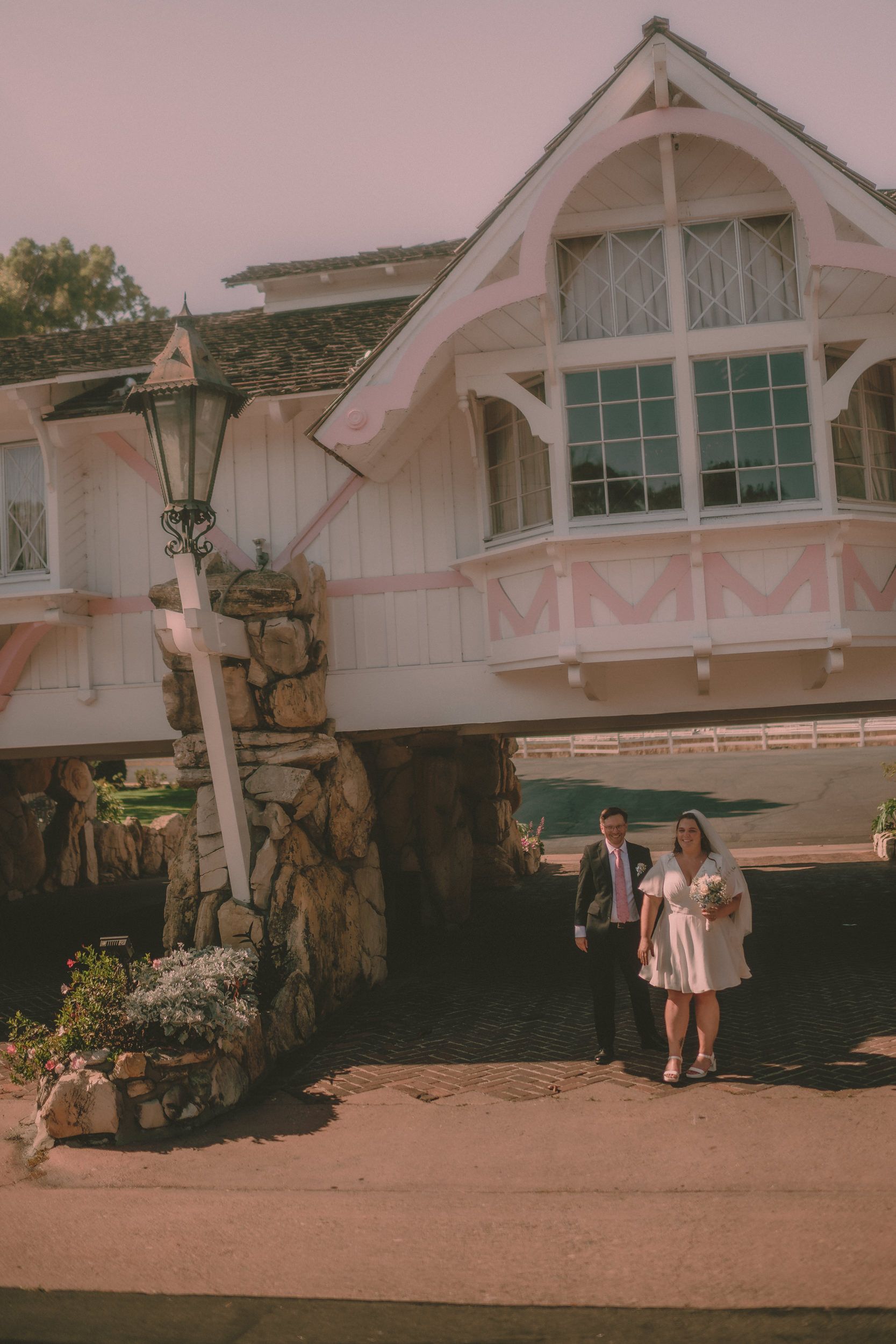 Tiffani and Braden stand small beneath the pink-and-stone Madonna Inn entrance.