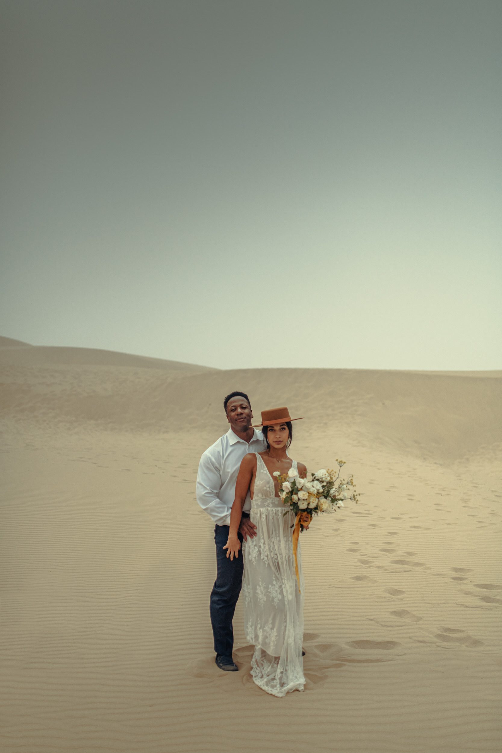 Couple standing together among coastal sand dunes