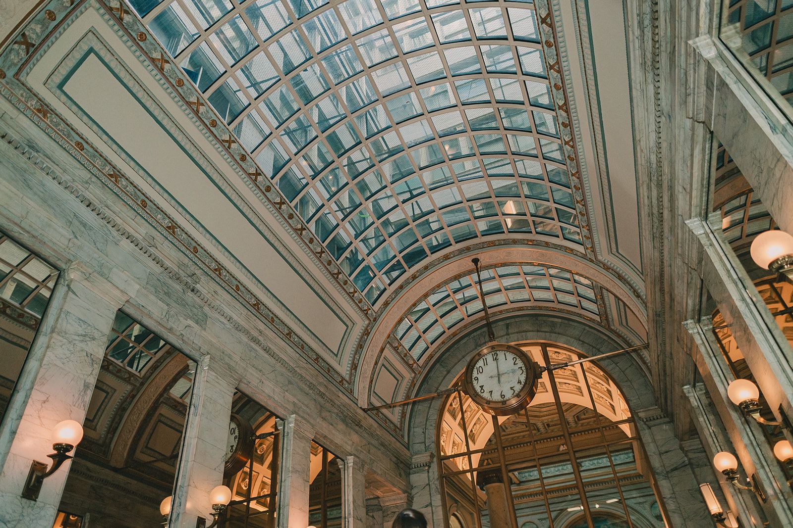 Wide architectural view of the Julia Morgan Ballroom clock beneath a glass and marble ceiling.
