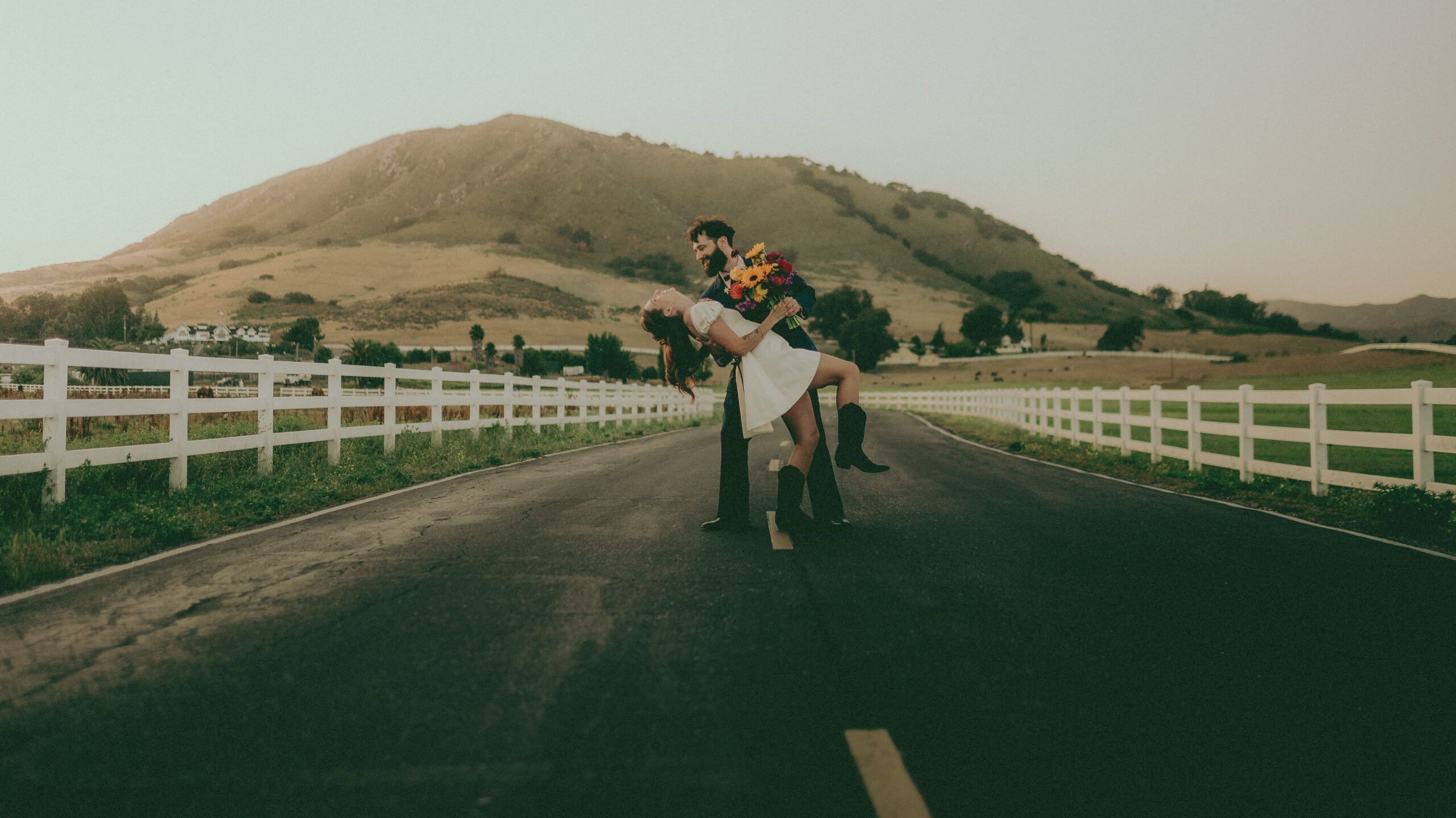 Emma and Jesse pose on a quiet road with rolling hills behind them