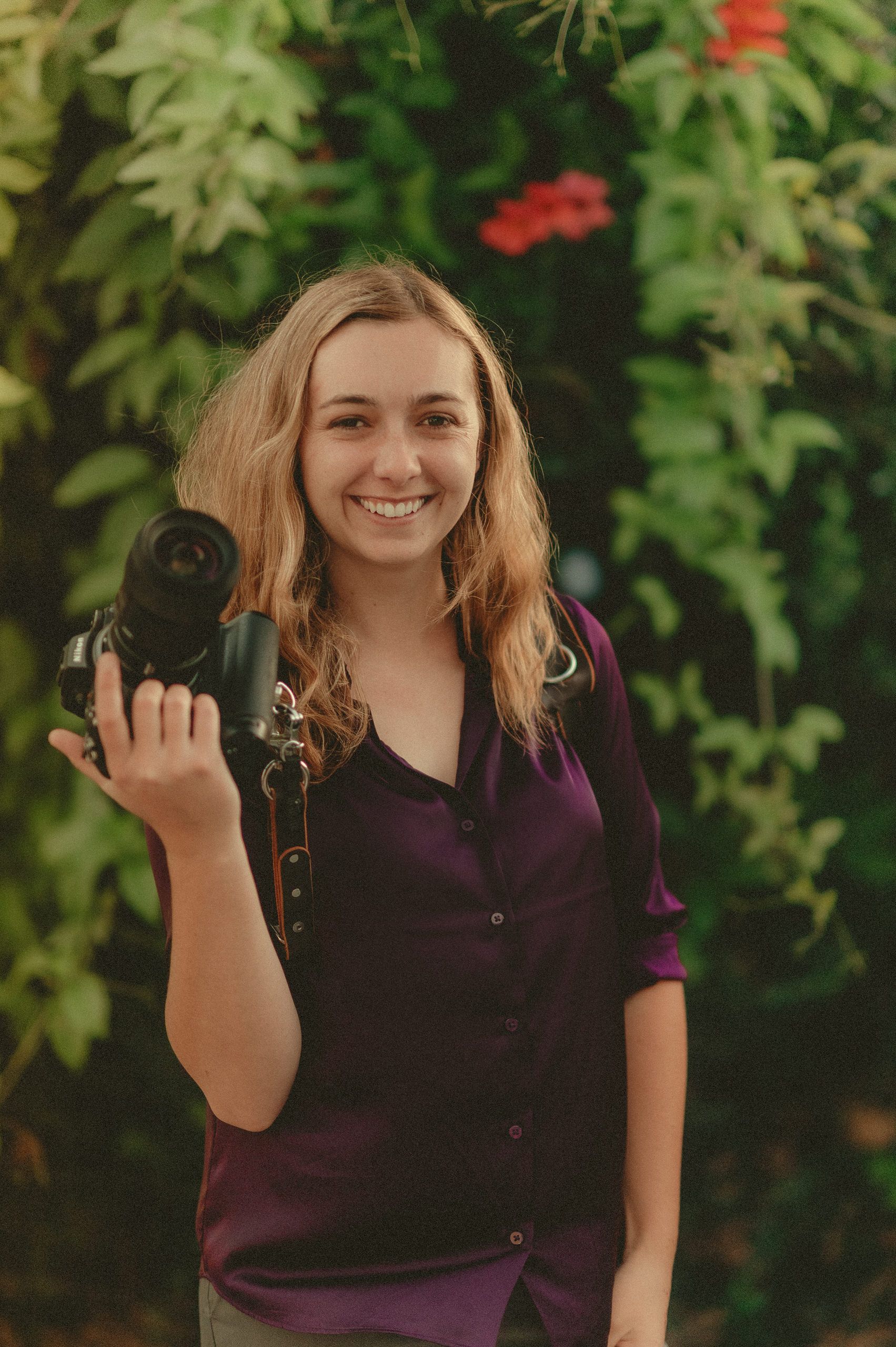 Makayla Grogan smiling with her camera outdoors.