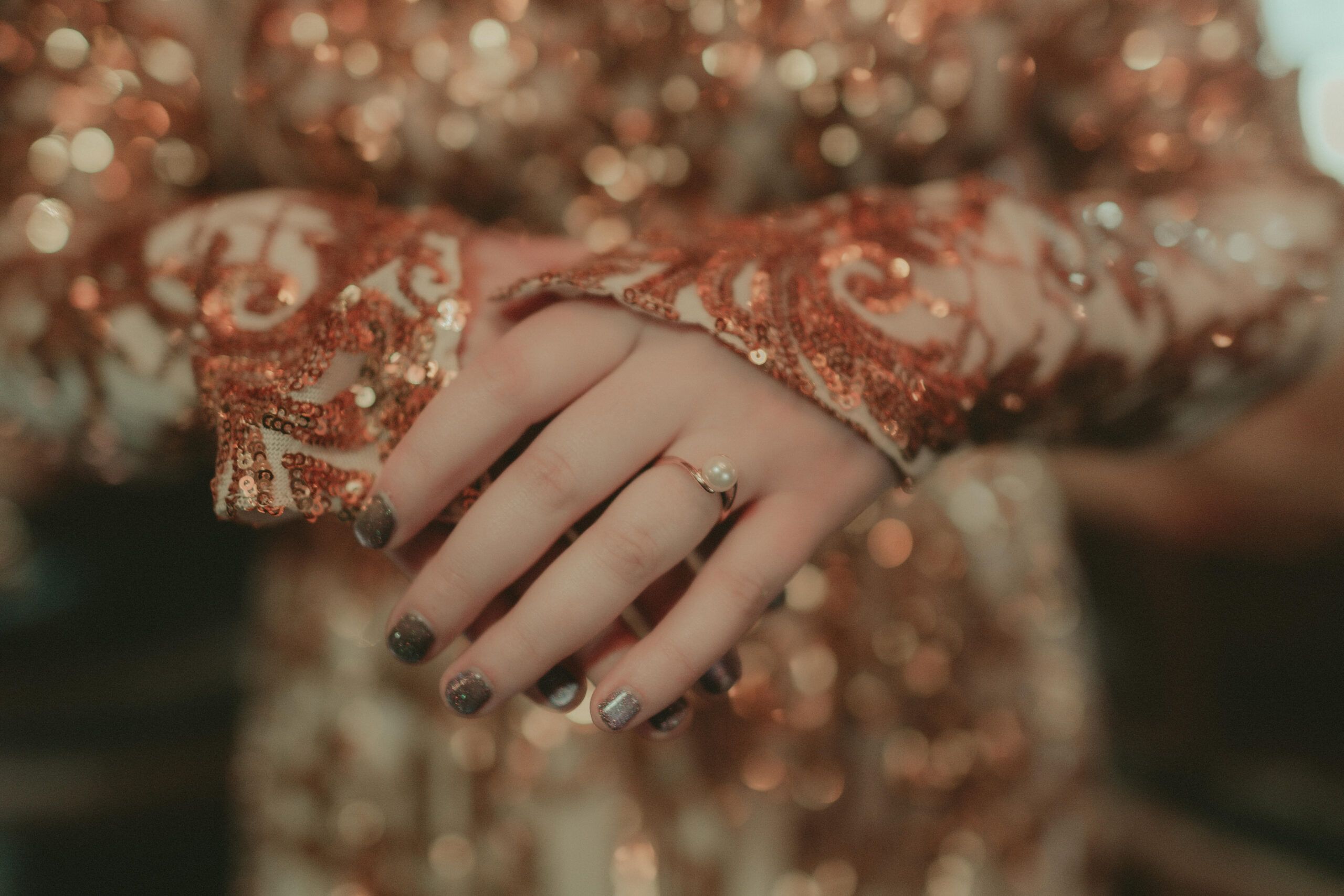 A pearl ring and glittering wedding attire photographed in close detail
