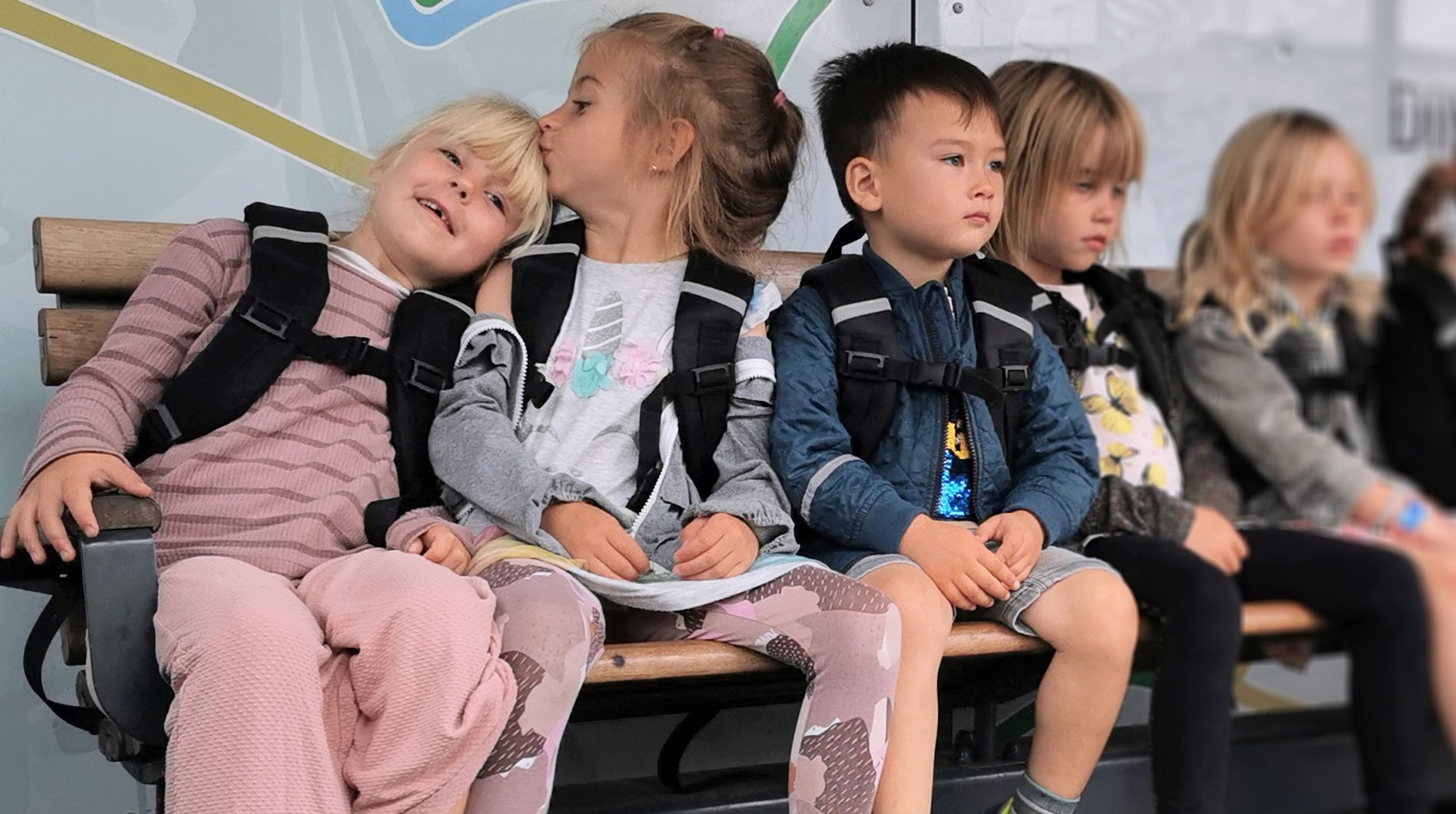 Børnehavebørn sidder på en bænk.