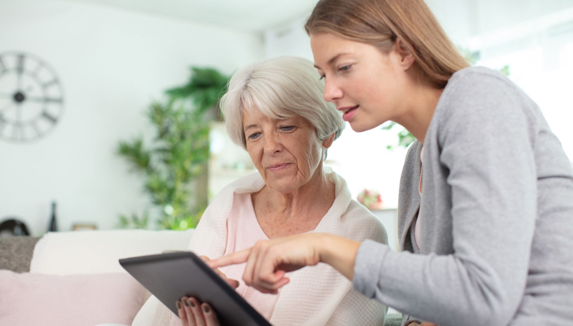 Medarbejder viser ældre borger, hvordan hun bruger sin ipad