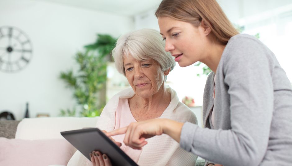 Medarbejder viser ældre borger, hvordan hun bruger sin ipad