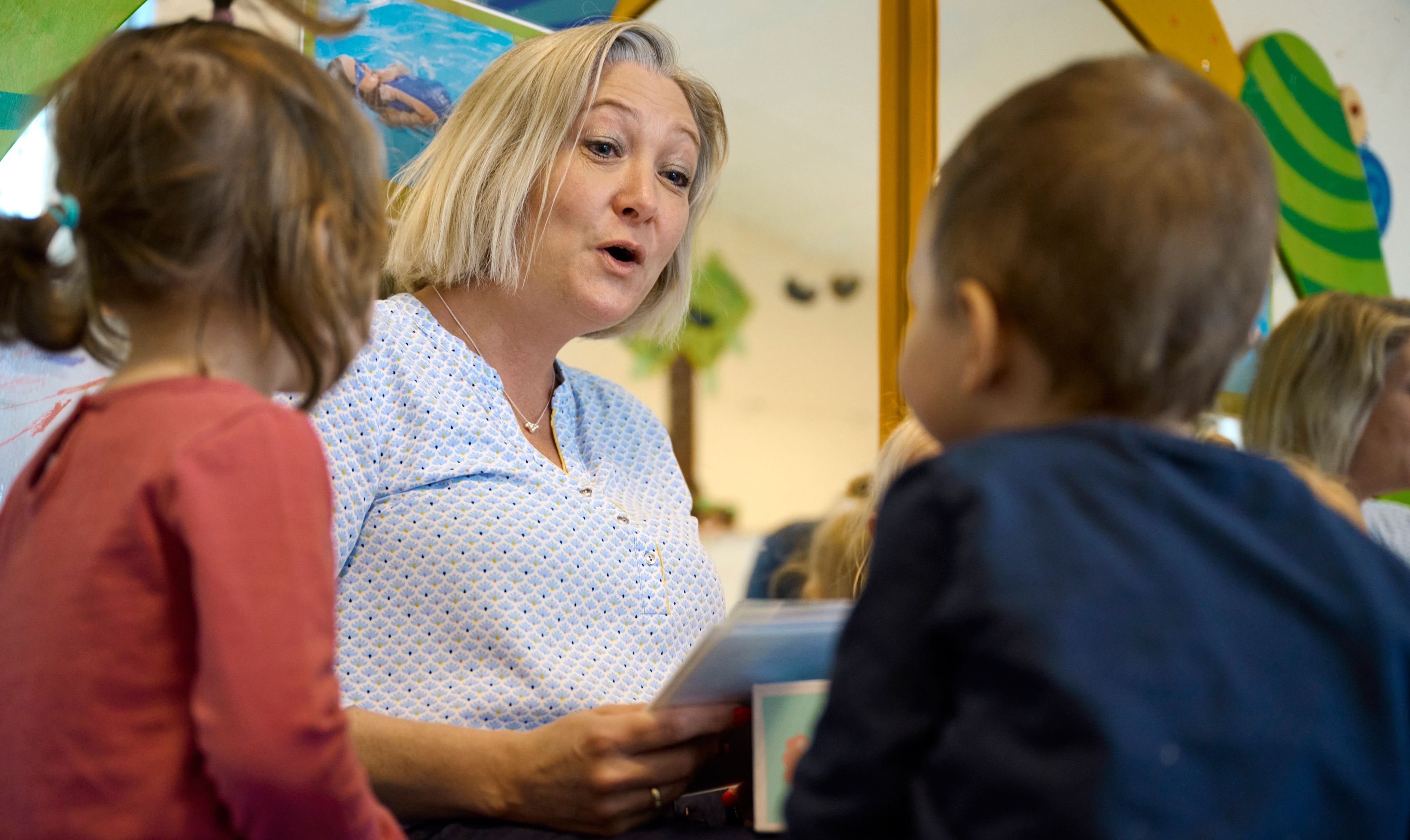 Pædagogmedhjælper læser historie for to børn