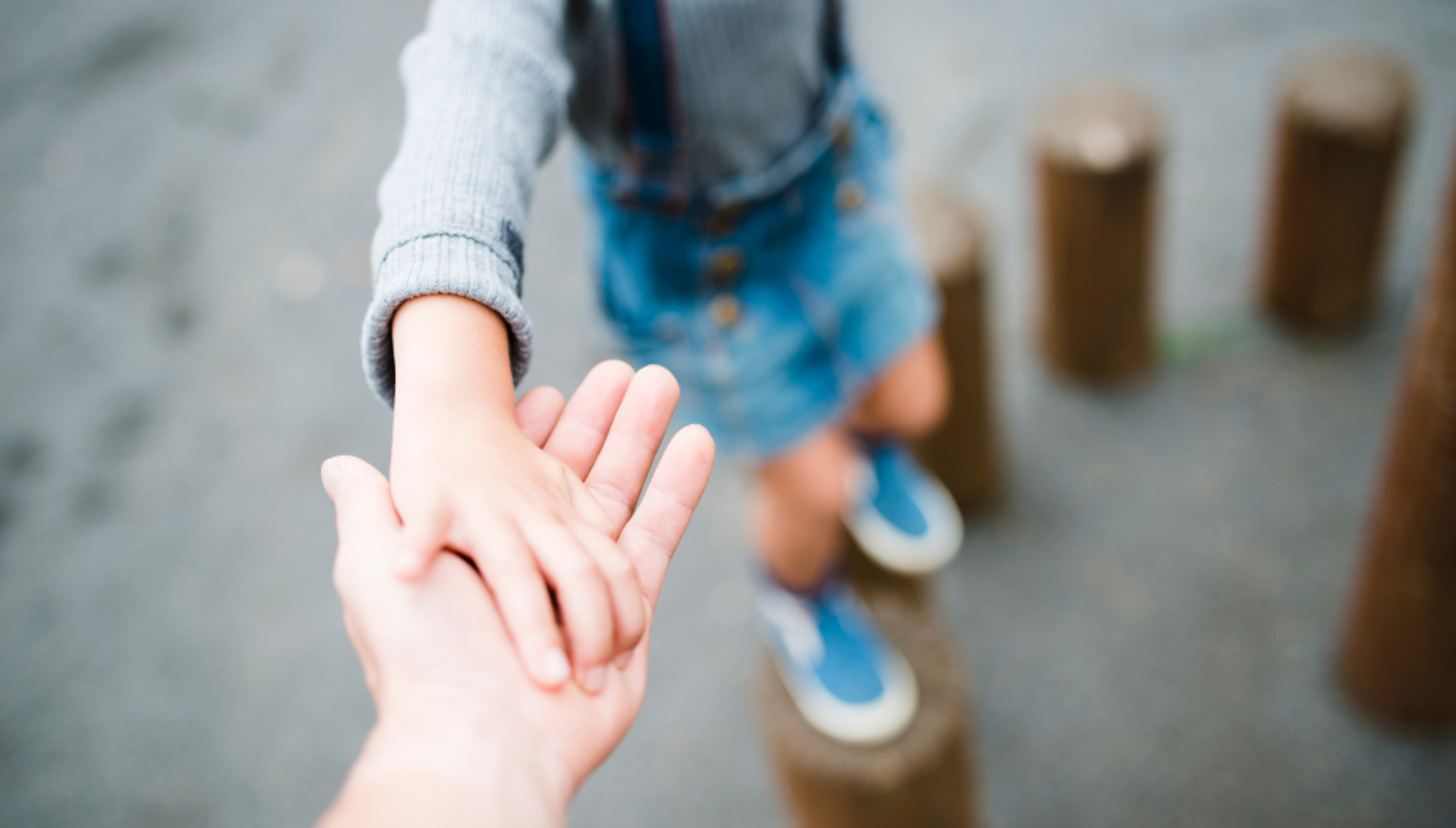 Barn balancerer og rækker en hånd ud til forælder
