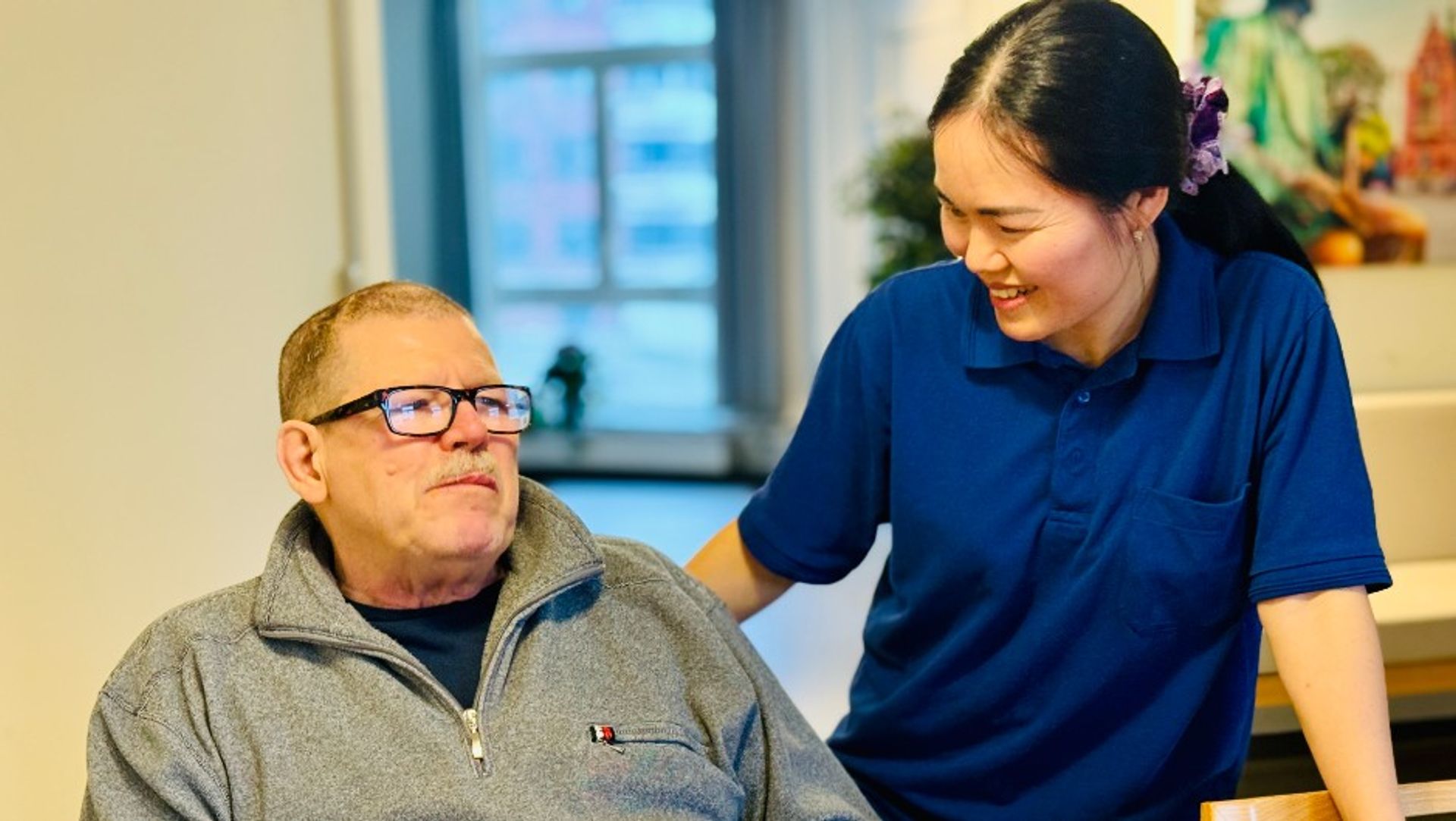 Omsorghjælper i samtale med ældre mand