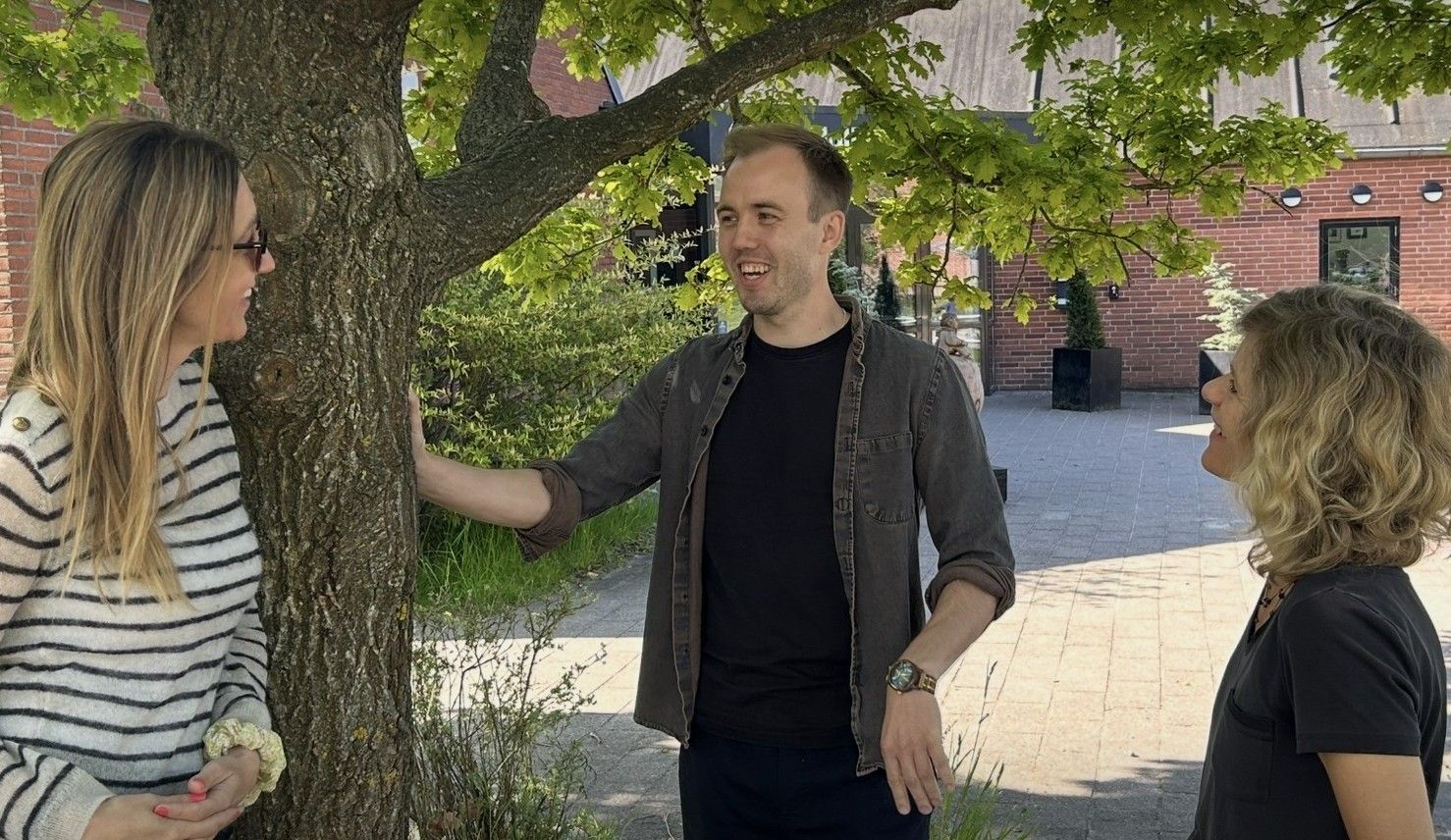 Karrierelærer står under et træ i skolegården og taler med skoleleder og UU-vejleder