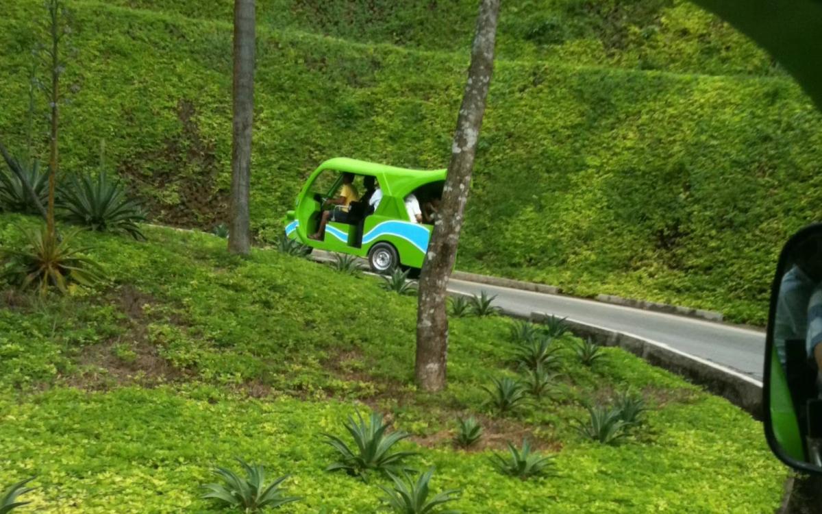 A green commercial-grade GerWeiss GE4 electric tricycle effortlessly navigating the steep, sloped terrain and narrow roads of Boracay island. Powered by a 150+ km range 5-Star lithium-ion battery, this zero-emission public utility vehicle carries up to 9 passengers while completely eliminating the noise and air pollution associated with traditional gasoline tricycles.
