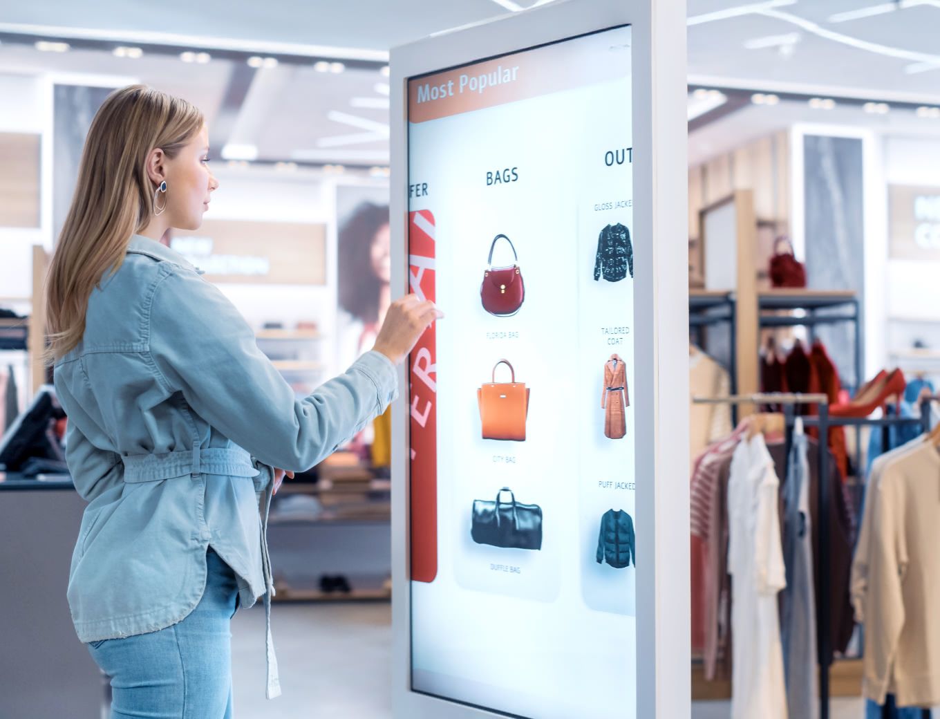 Woman using a large screen to scroll through fashion selections inside a retail store