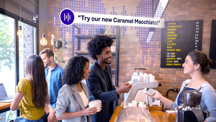 Two people ordering at the counter of a small cafe with Rockbot Audio Messaging playing in the background