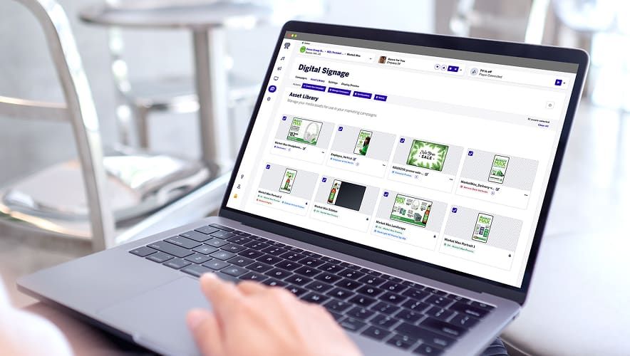 User managing digital signage content from the Rockbot Dashboard on a laptop.