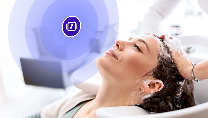 Salon guest relaxing during a hair appointment while on-brand music plays