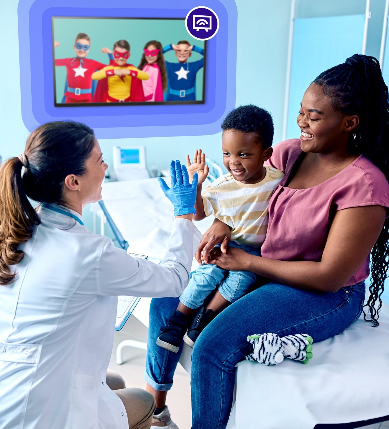 A child watching kid-friendly TV content during a pediatric medical visit while a clinician engages with the family.