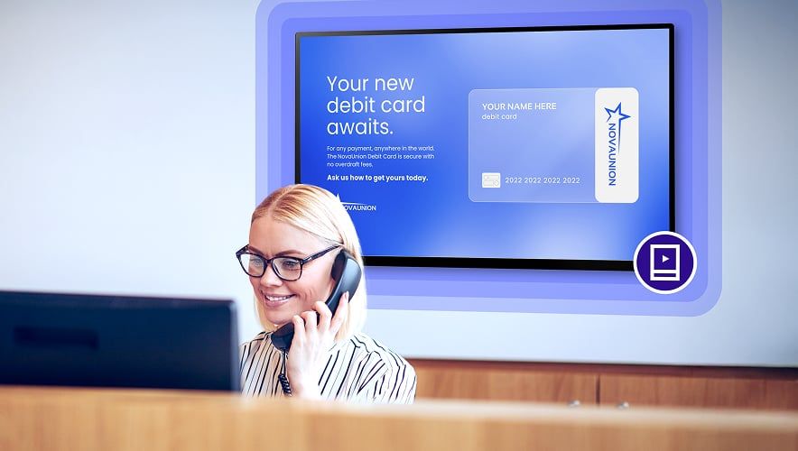 A bank employee on the phone while Rockbot Digital Signage is displayed in the background