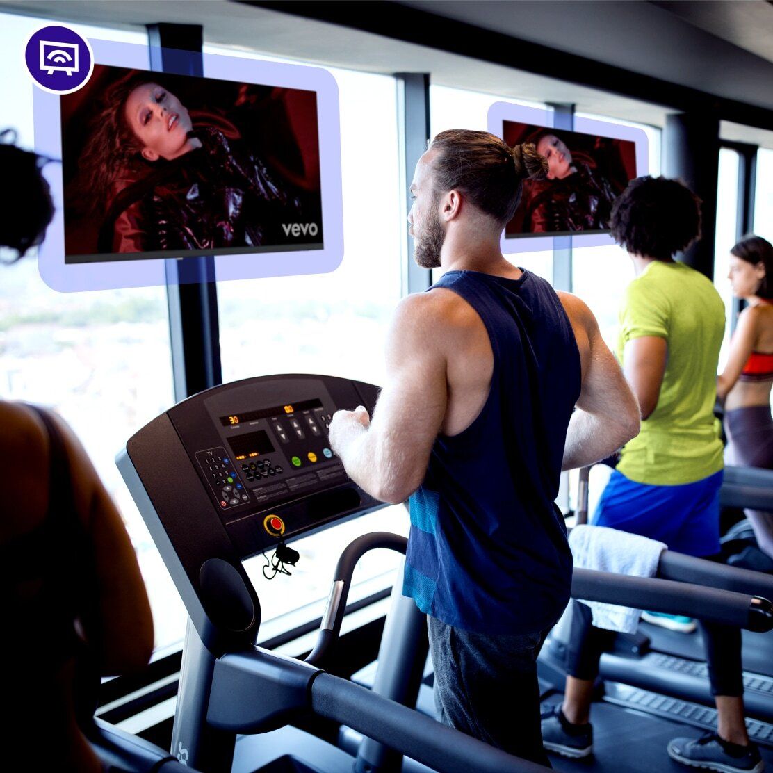Man on treadmill at gym with music videos playing on screen