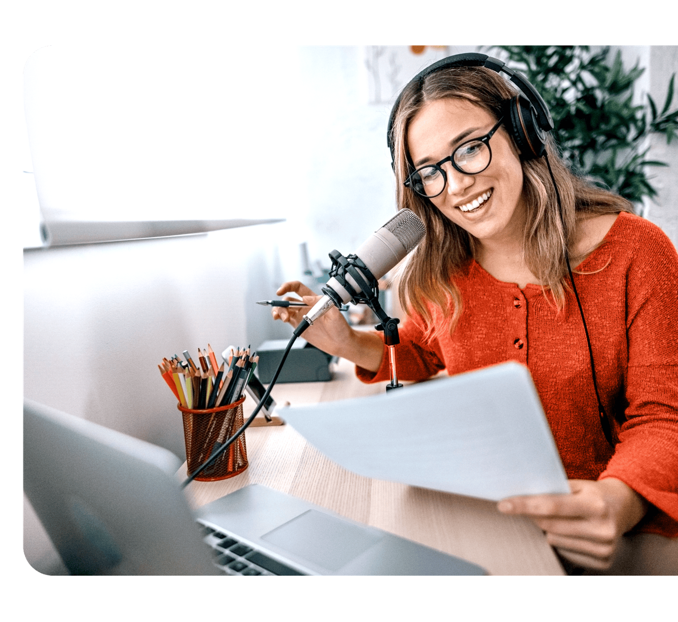 A woman wearing headphones at a microphone reviewing a script, representing Rockbot Audio Production's professional, end-to-end audio production service.