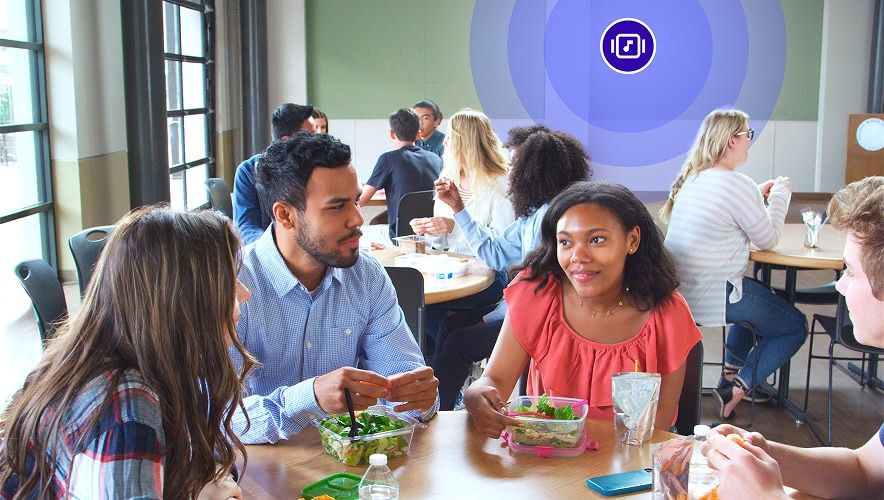 Students gathered at a campus dining hall table with background music playing