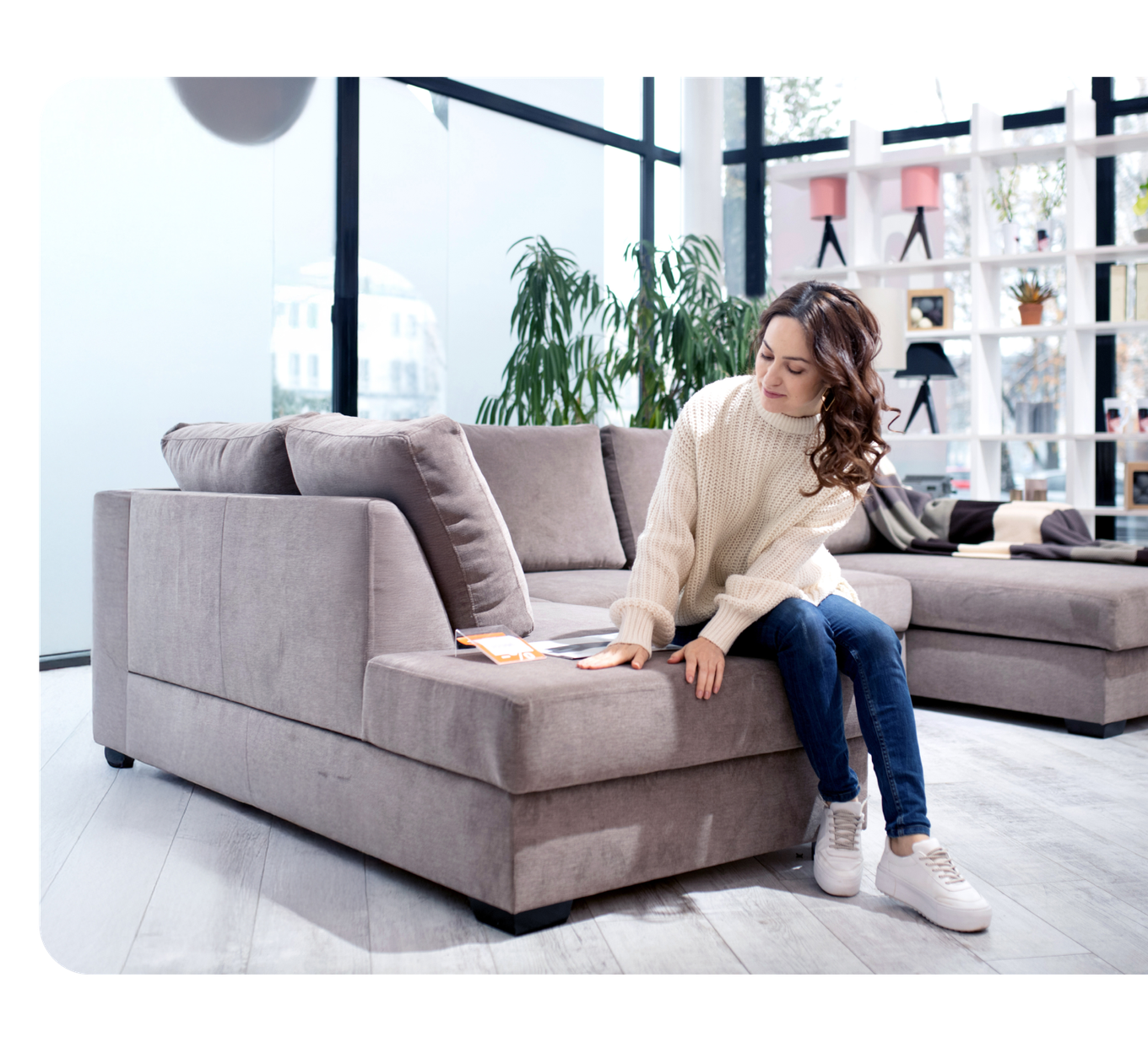 Image of a woman in a furniture store sitting on a couch that's for sale.